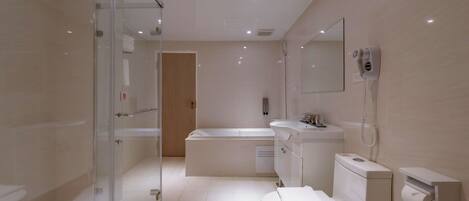 Un baño moderno con cabina de ducha de vidrio, bañera, inodoro y tocador con espejo.