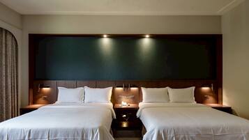Una habitación de hotel con dos camas, una pared grande de color oscuro e iluminación empotrada.