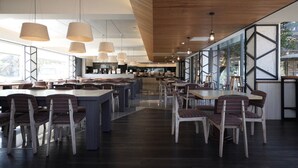A modern restaurant with a long counter, multiple tables, and chairs. - Haifu Garden Hotel (Jinsha)