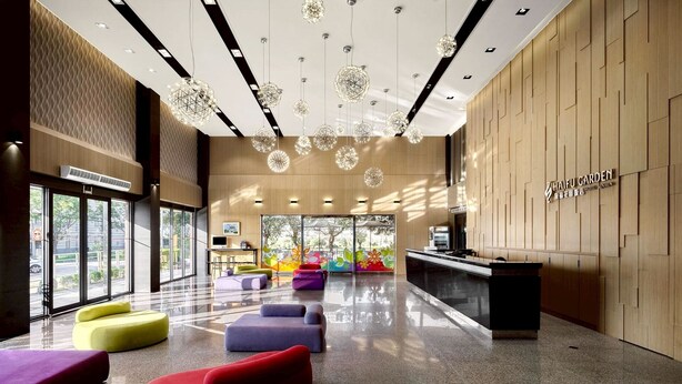A modern hotel lobby with a reception desk, colorful seating, and a large glass window offering a view of the outdoors. - Haifu Garden Hotel (Jinsha)
