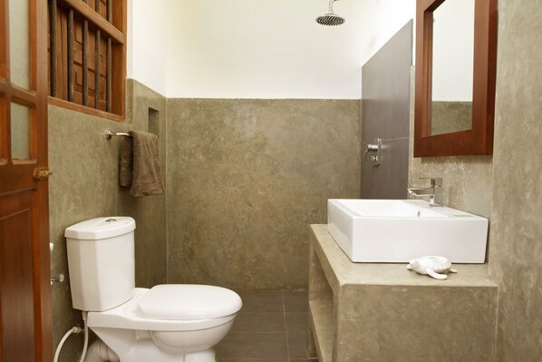 A compact bathroom with a toilet, a sink, and a shower.
