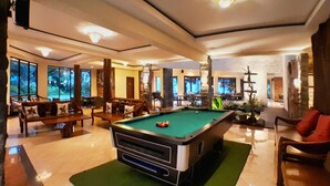 A pool table in a well-lit indoor space with large windows, comfortable seating, and a stone pillar. - The Batu Villas No 2 near Jatim Park (Batu)