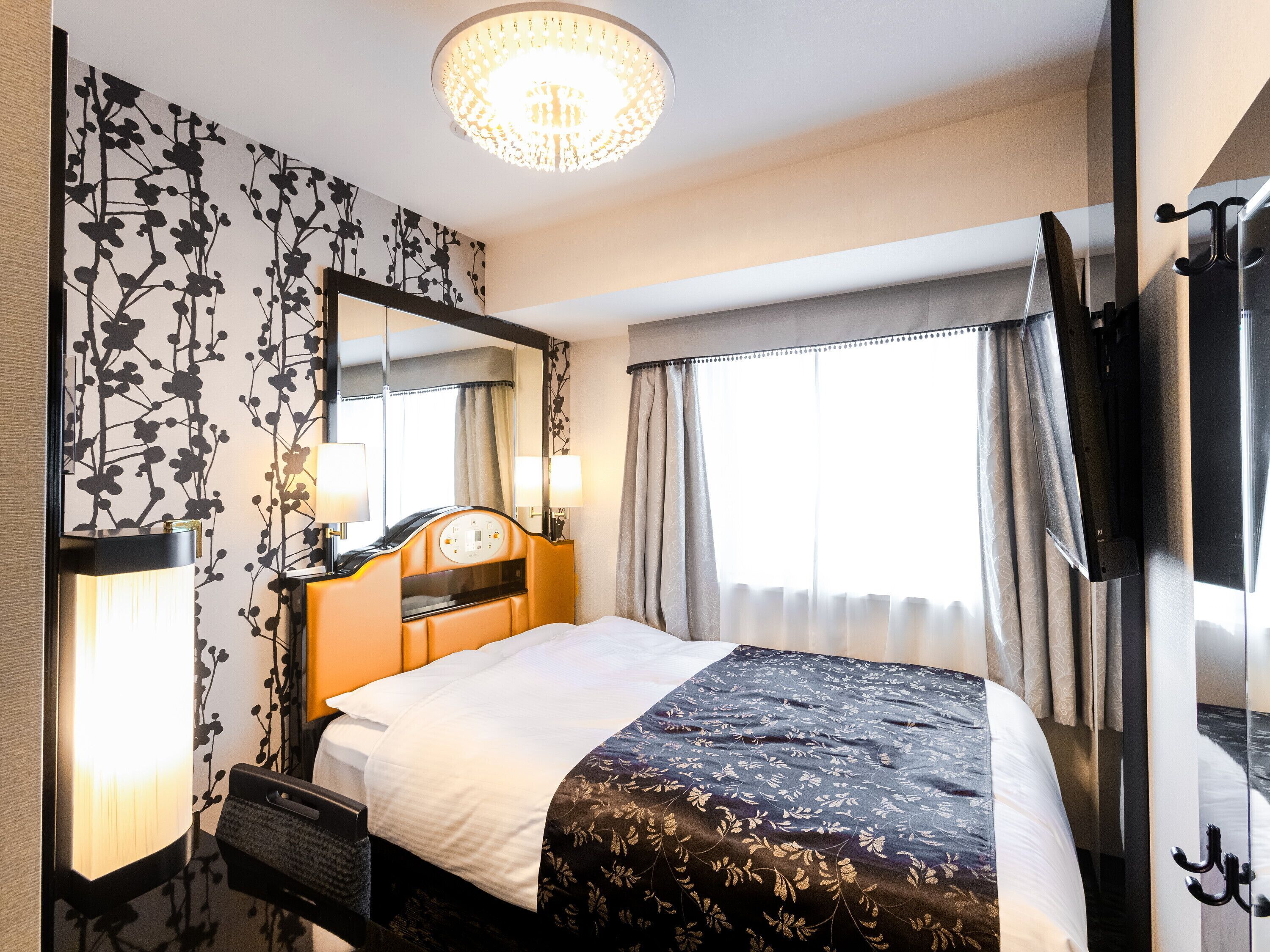 Una habitación de hotel con una cama grande, un espejo, una araña y un televisor.