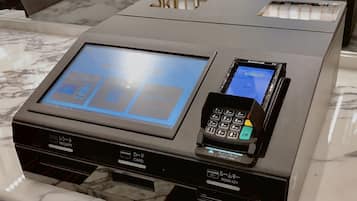A modern hotel reception desk with a digital screen, a card reader, and a small device for room key access.