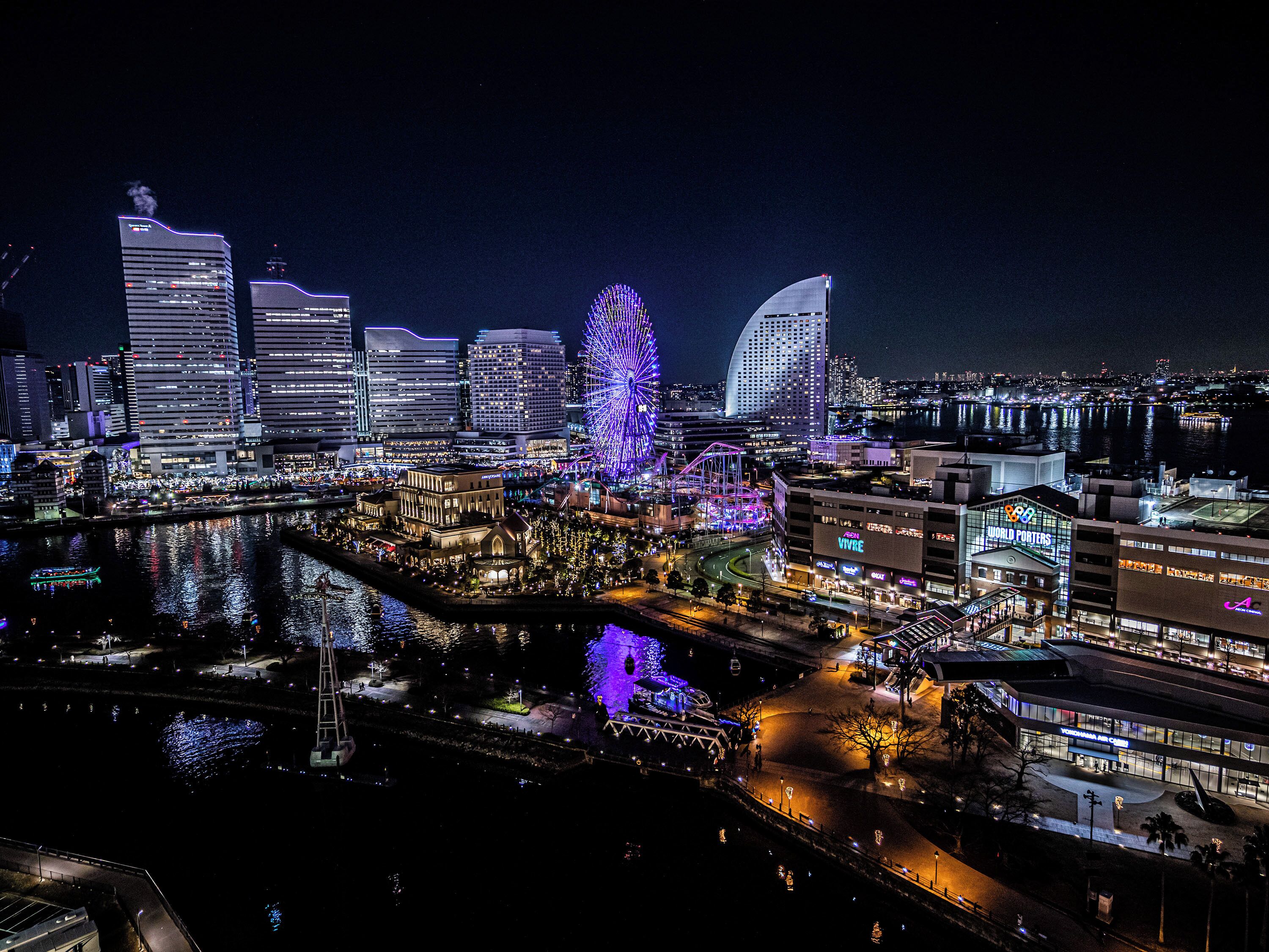 Un paisaje urbano nocturno con edificios iluminados, un río y un puente.