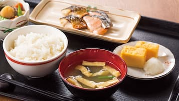 Una bandeja con un bol de arroz blanco, un bol de sopa de tofu, un plato con pescado y verduras, y un plato con cubos de tofu y un bollo.