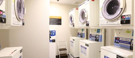 A laundry facility with multiple washing machines and dryers, each with instructional labels.