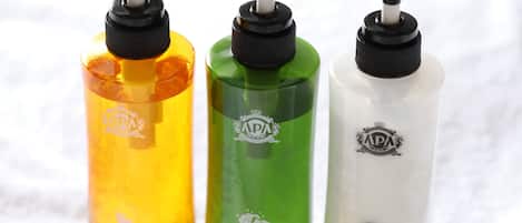 Tre flasker AP hotel toiletartikler: body wash, shampoo og balsam.