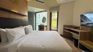 Een moderne hotelkamer met een groot bed, een televisie, een bureau en uitzicht op groen door het raam.