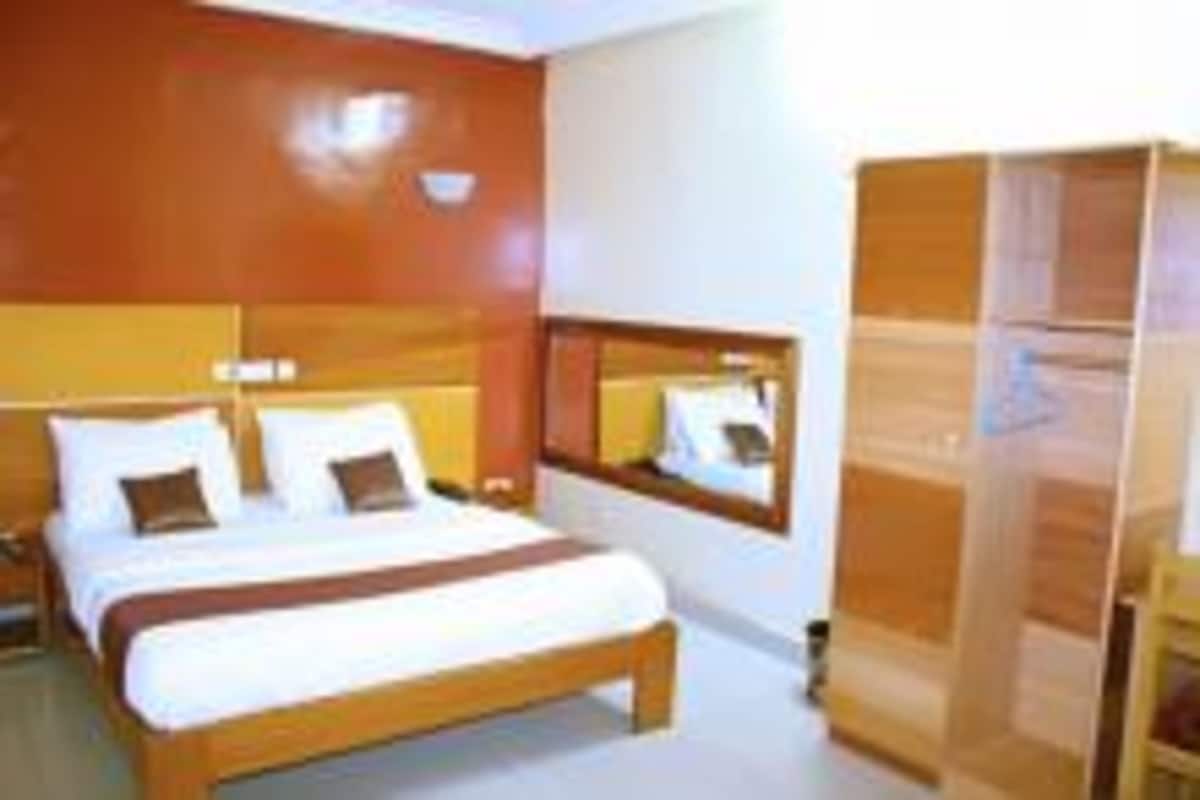 Une chambre d’hôtel avec un grand lit, une tête de lit en bois, un miroir et une armoire.