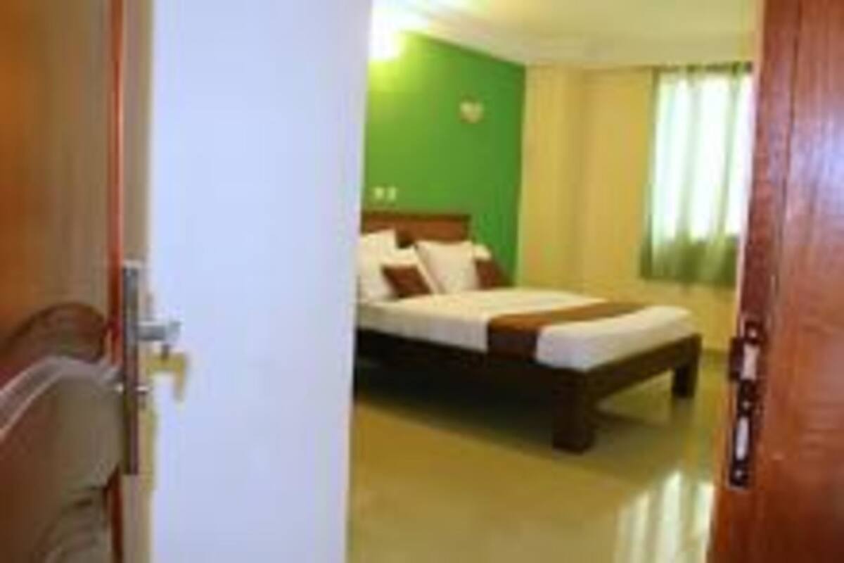 Une chambre d’hôtel avec un lit, une table de chevet et un mur vert.