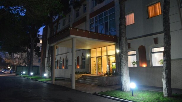 Entrada d'hotel amb un passadís cobert, escales que condueixen a l'entrada i una façana ben il·luminada.