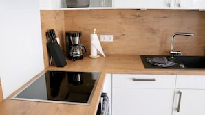Una cucina moderna con un piano di lavoro in legno, un piano cottura integrato, una macchina da caffè e un lavello.