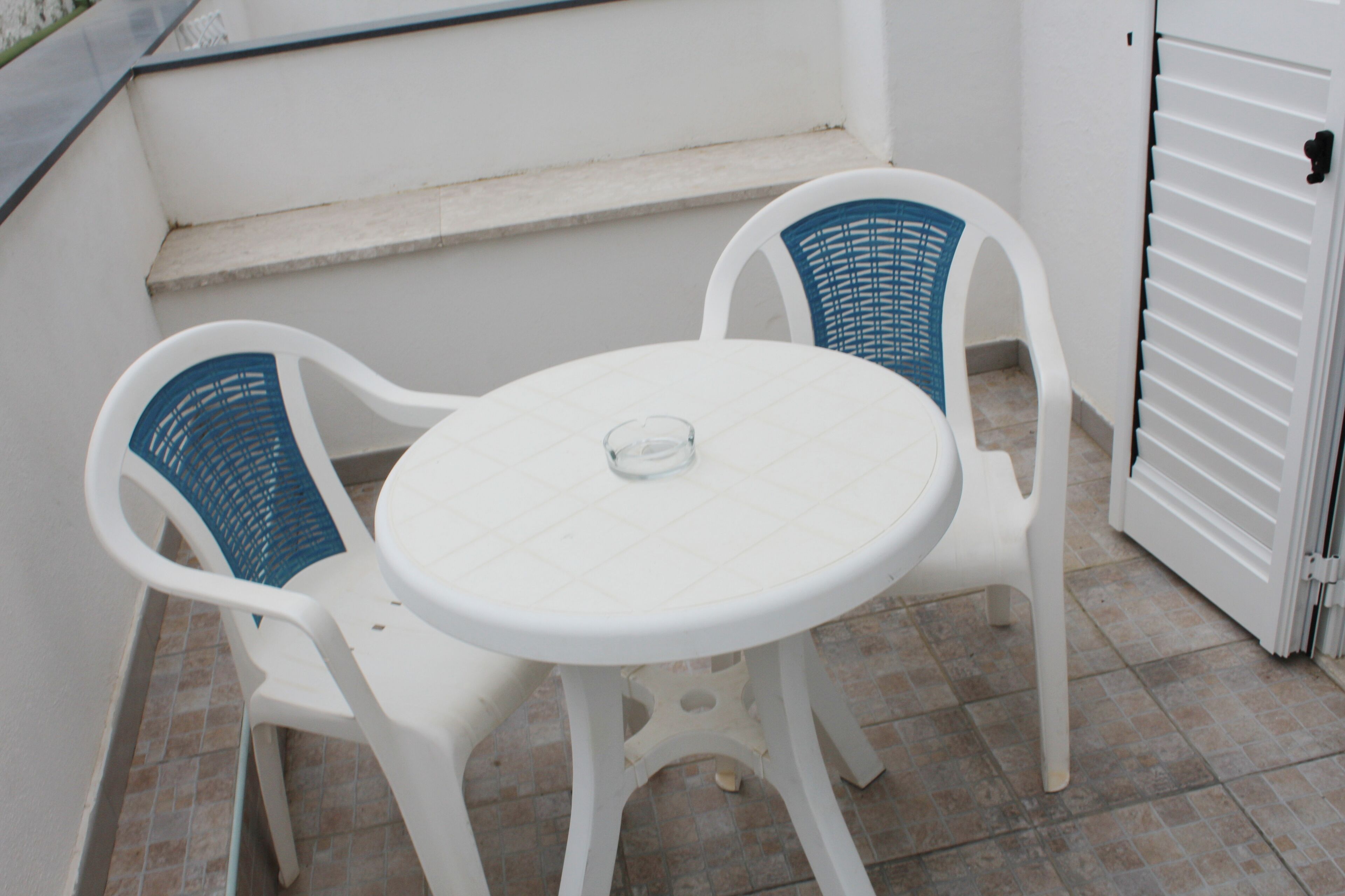 A small outdoor seating area with a round table and two chairs.