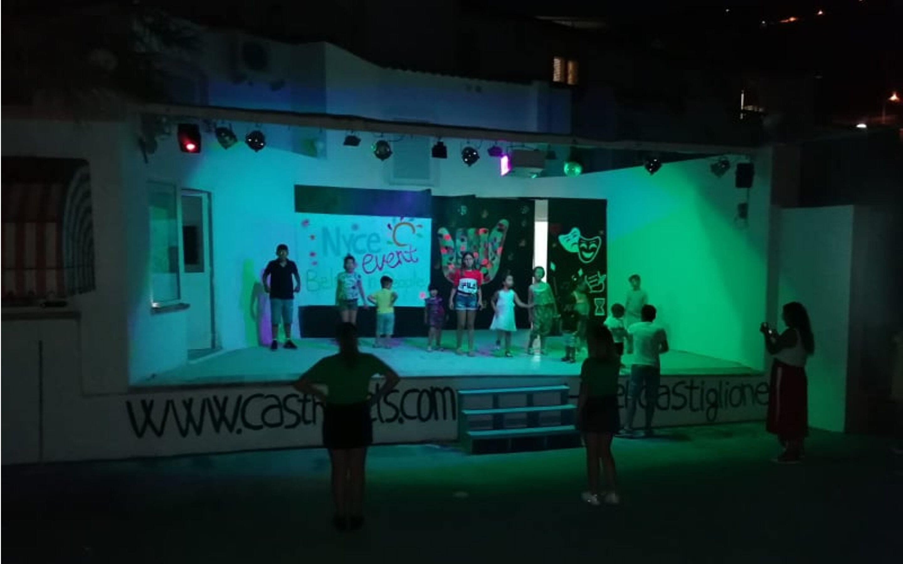 A stage with a group of people, a banner with text, and a website address.