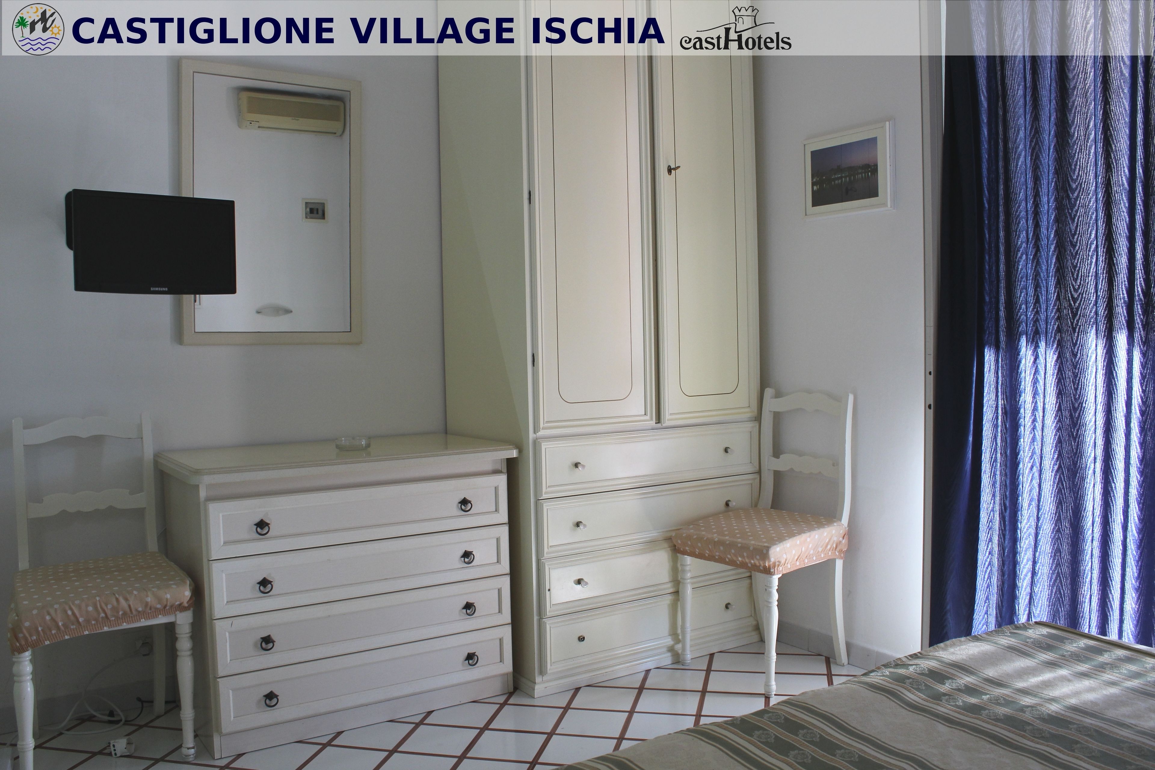 A bedroom with a bed, a dresser, a chair, a television, and a wardrobe.