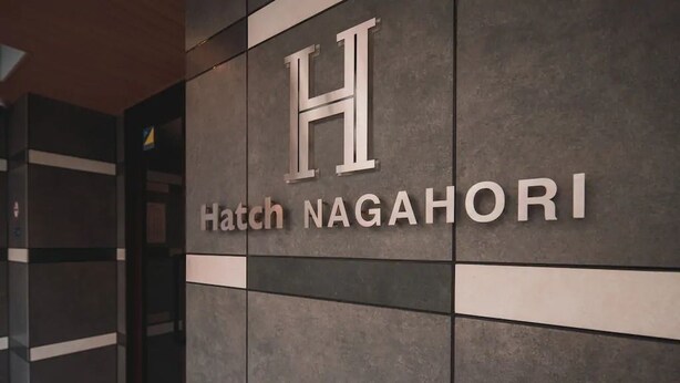Uma placa com as letras "H" e as palavras "Hatch NAGAHORI", indicando o nome do hotel.