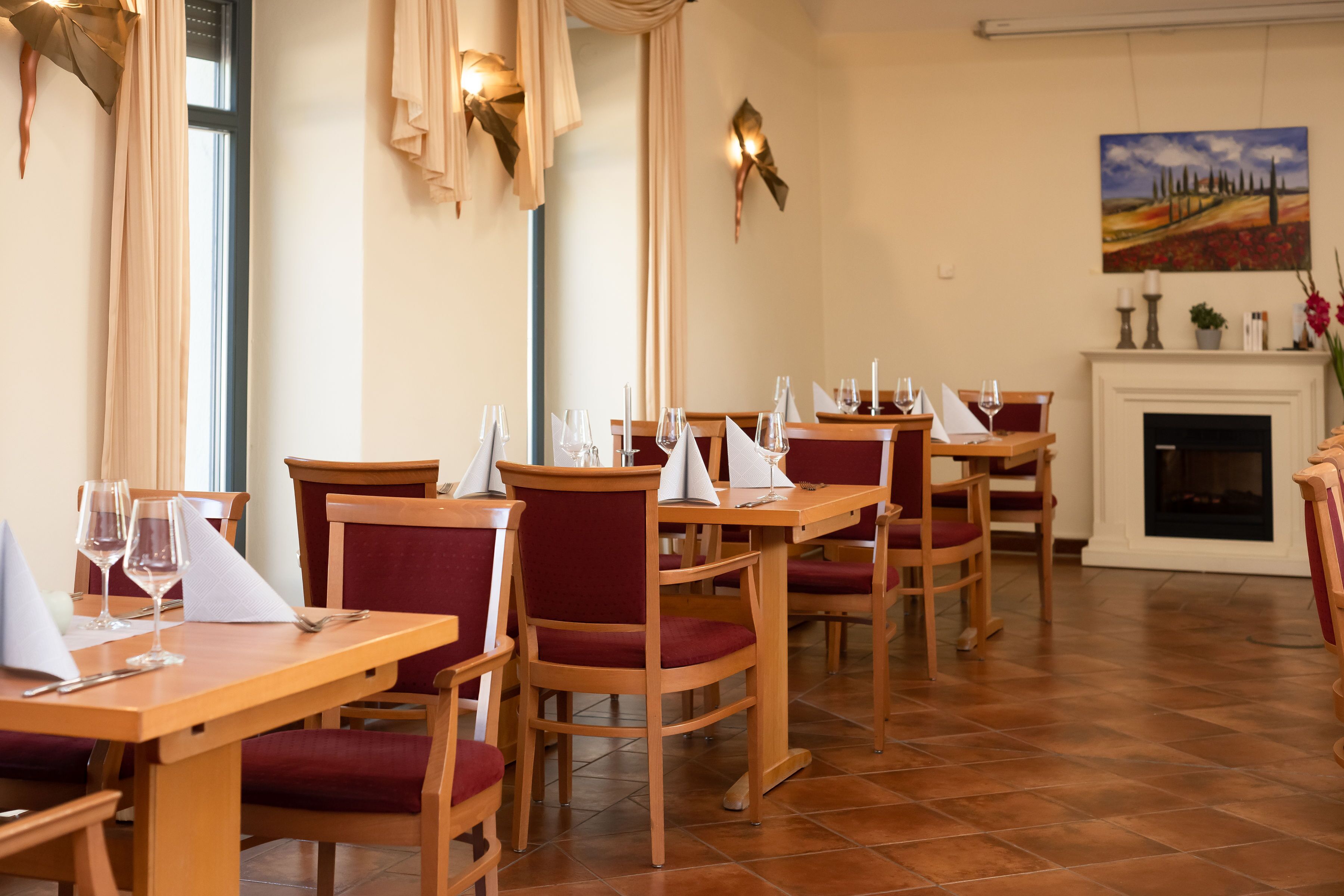 A dining area with wooden tables and red upholstered chairs.