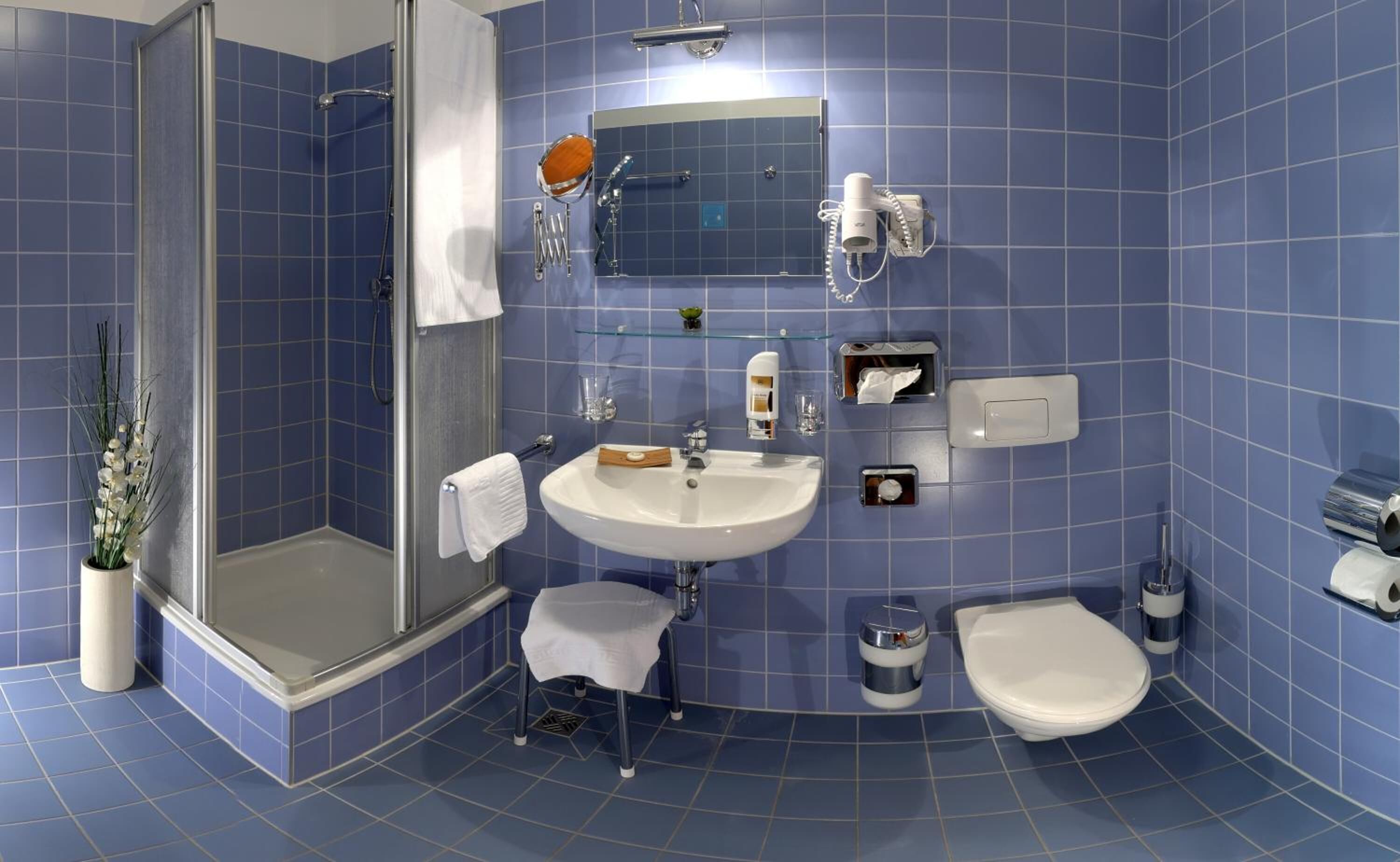 A bathroom with a shower, sink, toilet, and a mirror.