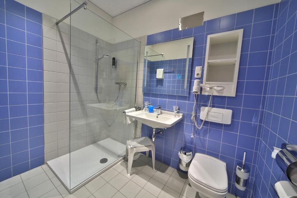 Un baño con ducha de vidrio, lavamanos, inodoro y espejo.