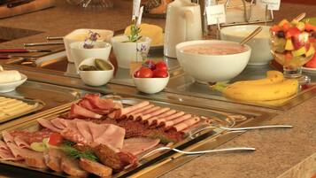 Un bufé con diversos alimentos, incluyendo carnes, quesos y frutas.