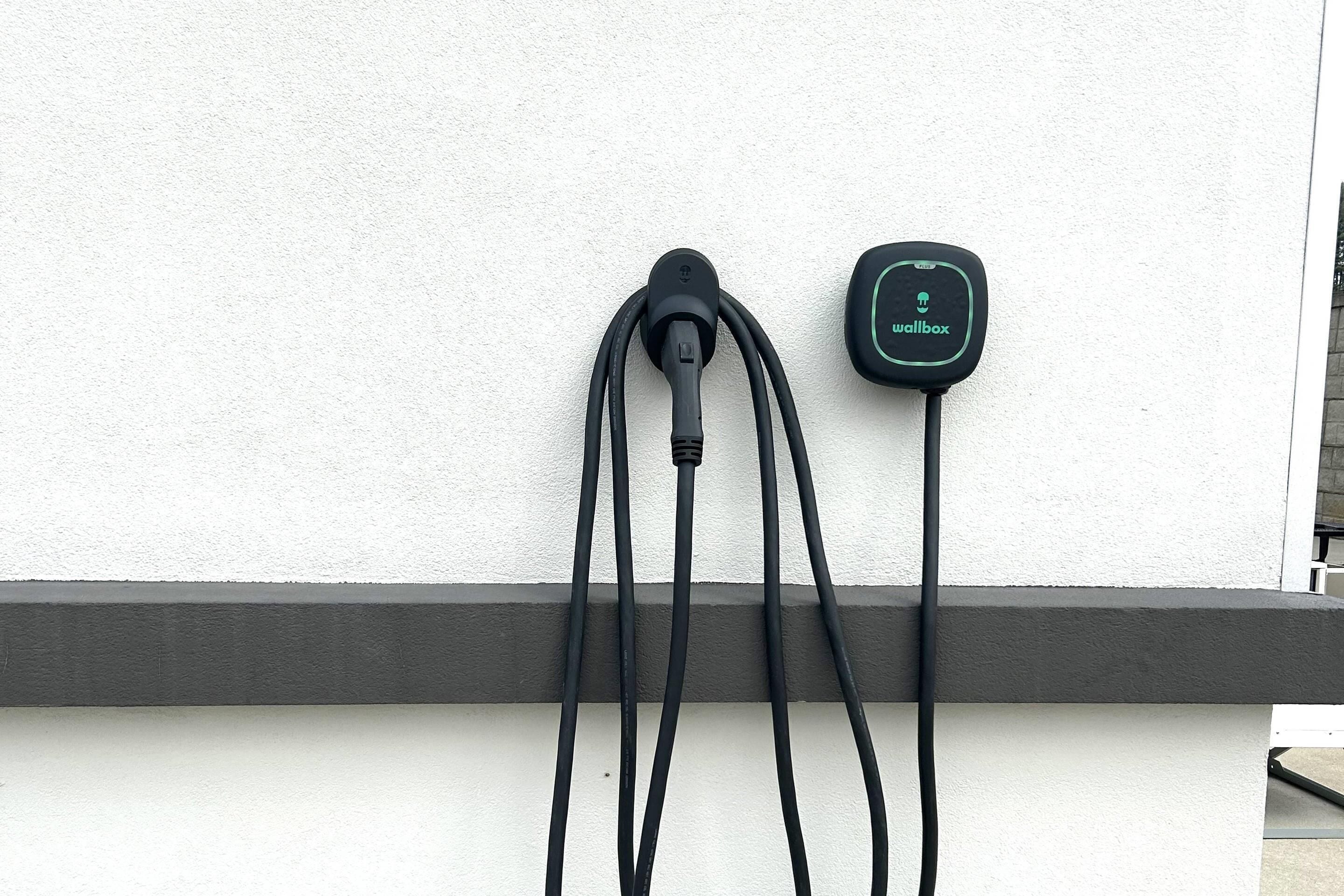 A wall-mounted charging station with a cable and a wallbox.