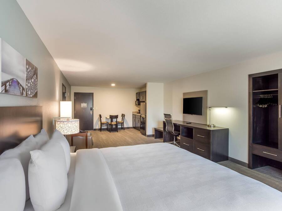 A hotel room with a large bed, a desk with a chair, a wardrobe, and a television.