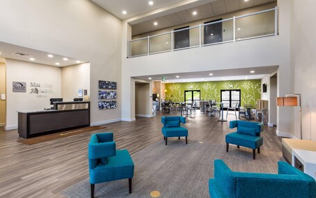 A spacious lobby with a reception desk, multiple seating areas, and a green wall with floral decorations.