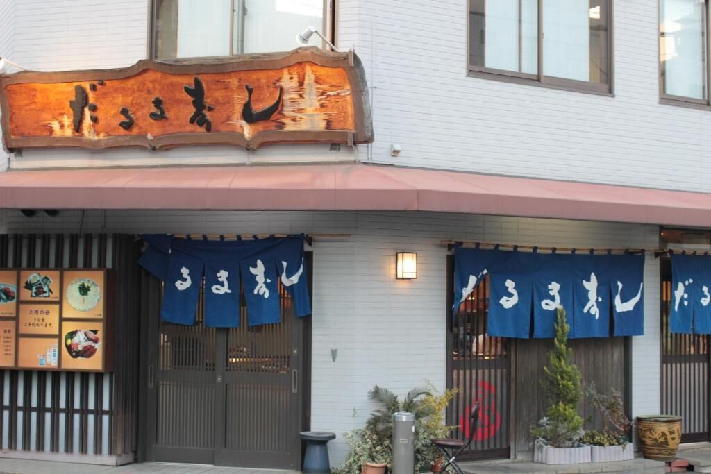 Un restaurant avec une enseigne japonaise traditionnelle et des auvents bleus.