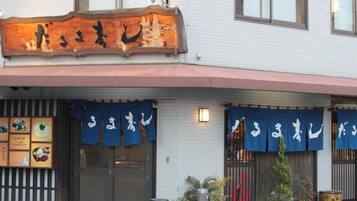 Un restaurant avec une enseigne japonaise traditionnelle et des auvents bleus.