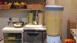 A kitchen with a blender, a small refrigerator, and baskets of fruits on shelves. - Guest House COCO Hiroshima - Hostel, Caters to Women (Hiroshima)