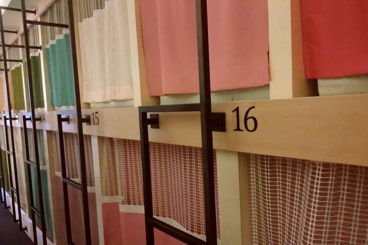 Une rangée de chambres d’hôtel numérotées, chacune ayant des rideaux de couleur différente.