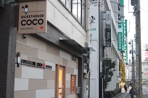 Un bâtiment sur lequel on peut lire l’inscription « Guesthouse Coco Hiroshima » et où le numéro « 3298 » est peint sur le mur.