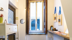 A compact kitchen with a window, hanging lights, and a welcome mat. - Napoli Napoli (Naples)