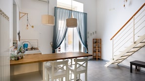 A modern kitchen with a wooden table, white chairs, and a built-in sink. - Napoli Napoli (Naples)