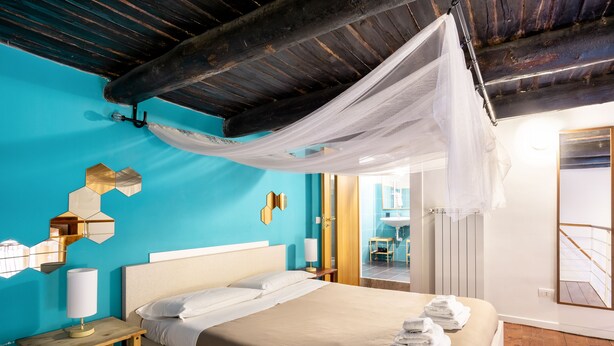 A bedroom with a bed, a bedside table with a lamp, a mirror, and a bathroom visible through an open door. - Napoli Napoli (Naples)
