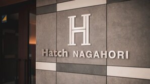 A sign with the letter "H" and the words "Hatch NAGAHORI" on a tiled wall. - Hatch NAGAHORI 701 (Osaka)