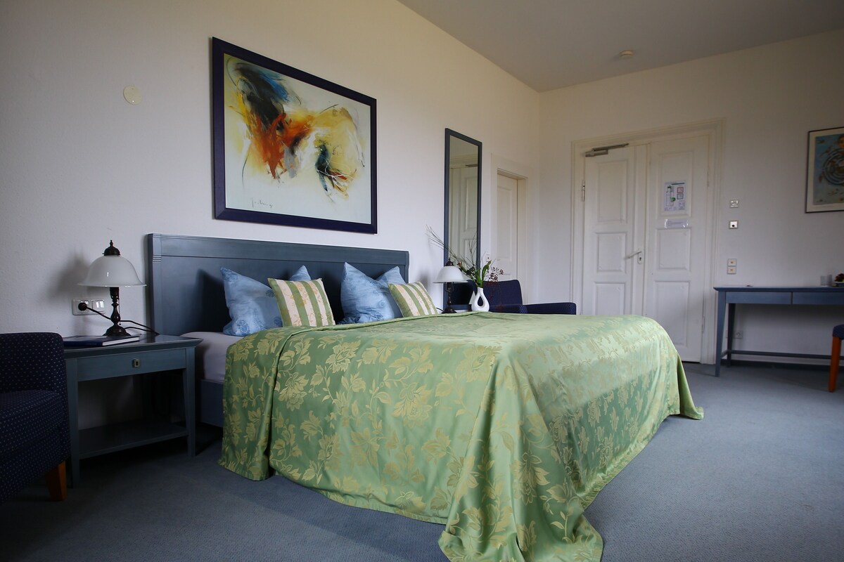 A neatly arranged bedroom with a bed, bedside tables, a desk, and a chair.