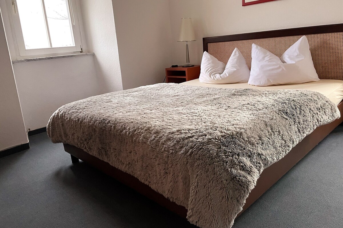 A neatly made bed with a textured blanket, a wooden headboard, and white pillows.