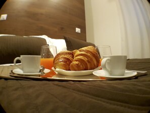 Una bandeja con cruasanes, jugo de naranja y café para el desayuno.