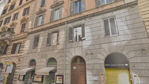Un edificio histórico con varias fachadas comerciales, que incluye una tienda de frutas y verduras, un depósito de equipaje y una cámara frigorífica.