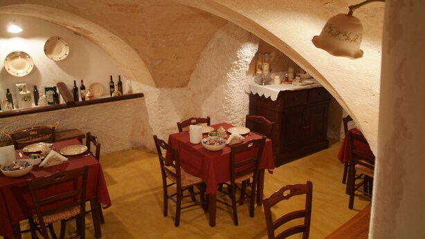 Comedor con una mesa dispuesta para cuatro personas, sillas alrededor y una estantería con botellas de vino.