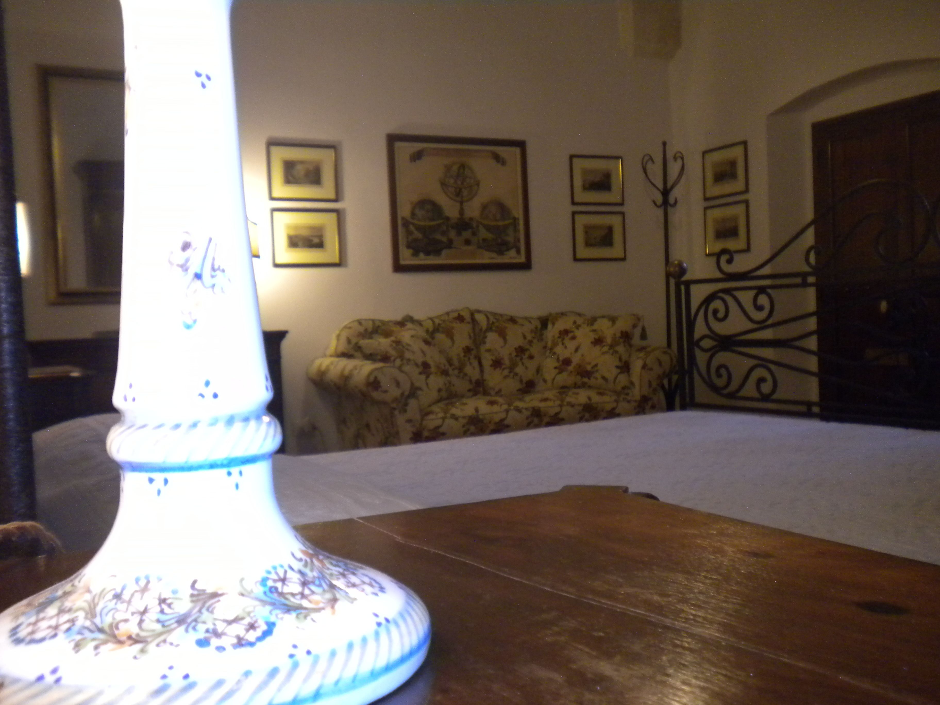 Una habitación con una mesa de madera, un sofá floral y una pared con cuadros.