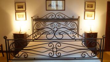 A bed with a wrought iron headboard, two bedside tables, and framed pictures on the walls.