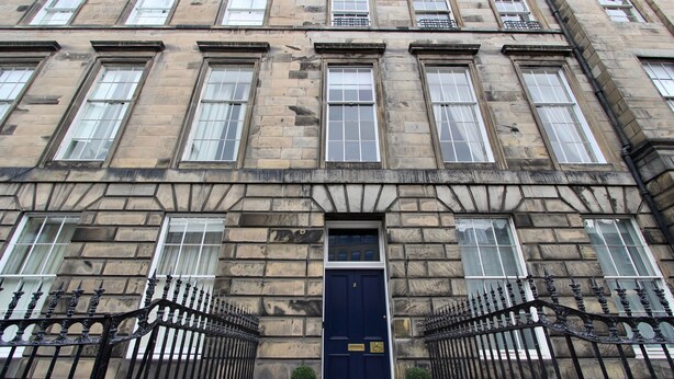 A historic building with a dark blue door, multiple windows, and a stone facade.