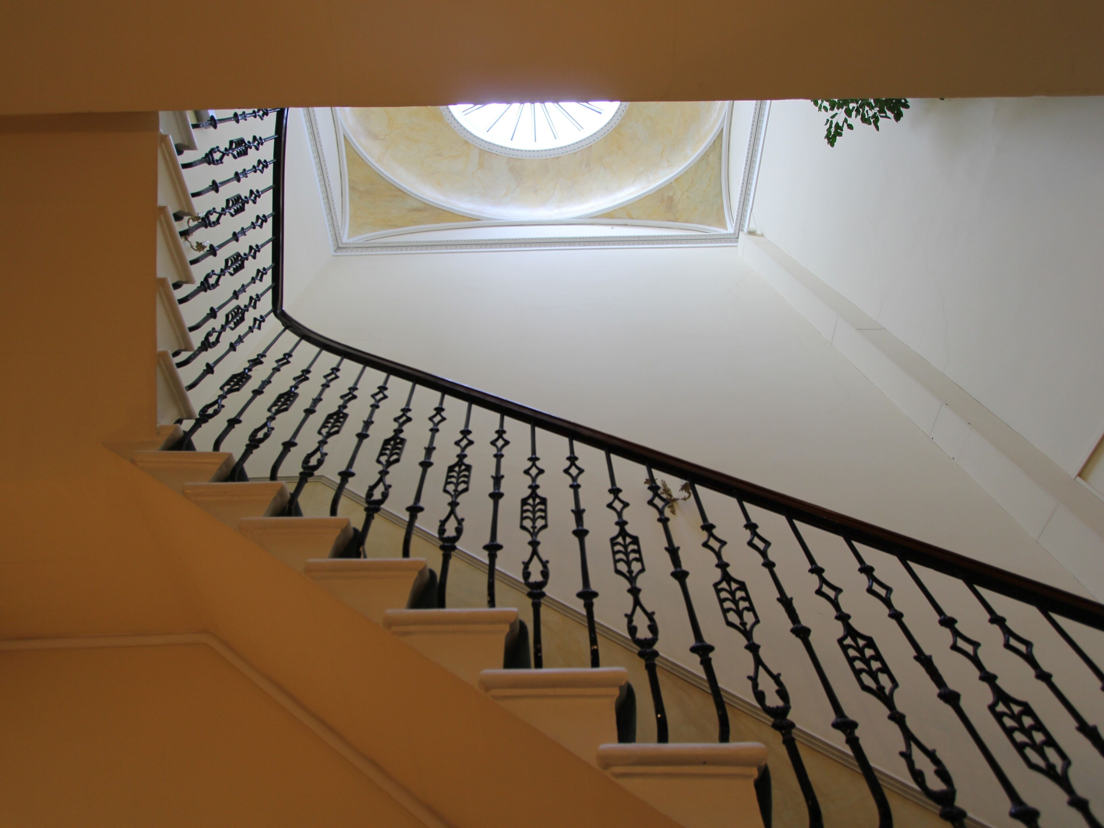 Eine Treppe mit aufwendig gestalteten schwarzen Geländern und einem Oberlicht.