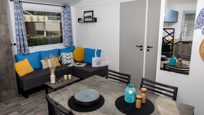 Un espacio habitable compacto con sofá, mesa de comedor y zona de cocina.