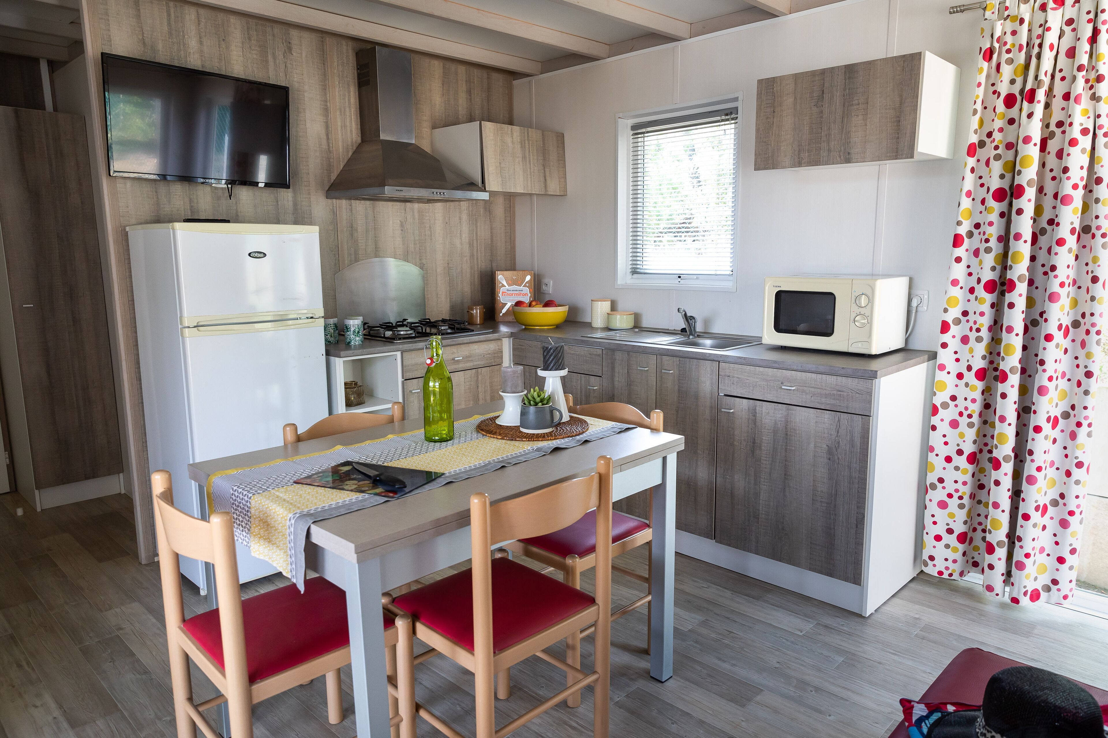 Une cuisine compacte équipée d’un réfrigérateur, d’une cuisinière, d’un four à micro-ondes et d’un coin repas avec une table et des chaises.