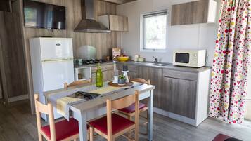 Une cuisine compacte équipée d’un réfrigérateur, d’une cuisinière, d’un four à micro-ondes et d’un coin repas avec une table et des chaises.
