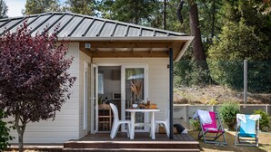 Una casa pequeña con porche, una mesa de comedor y dos sillas.
